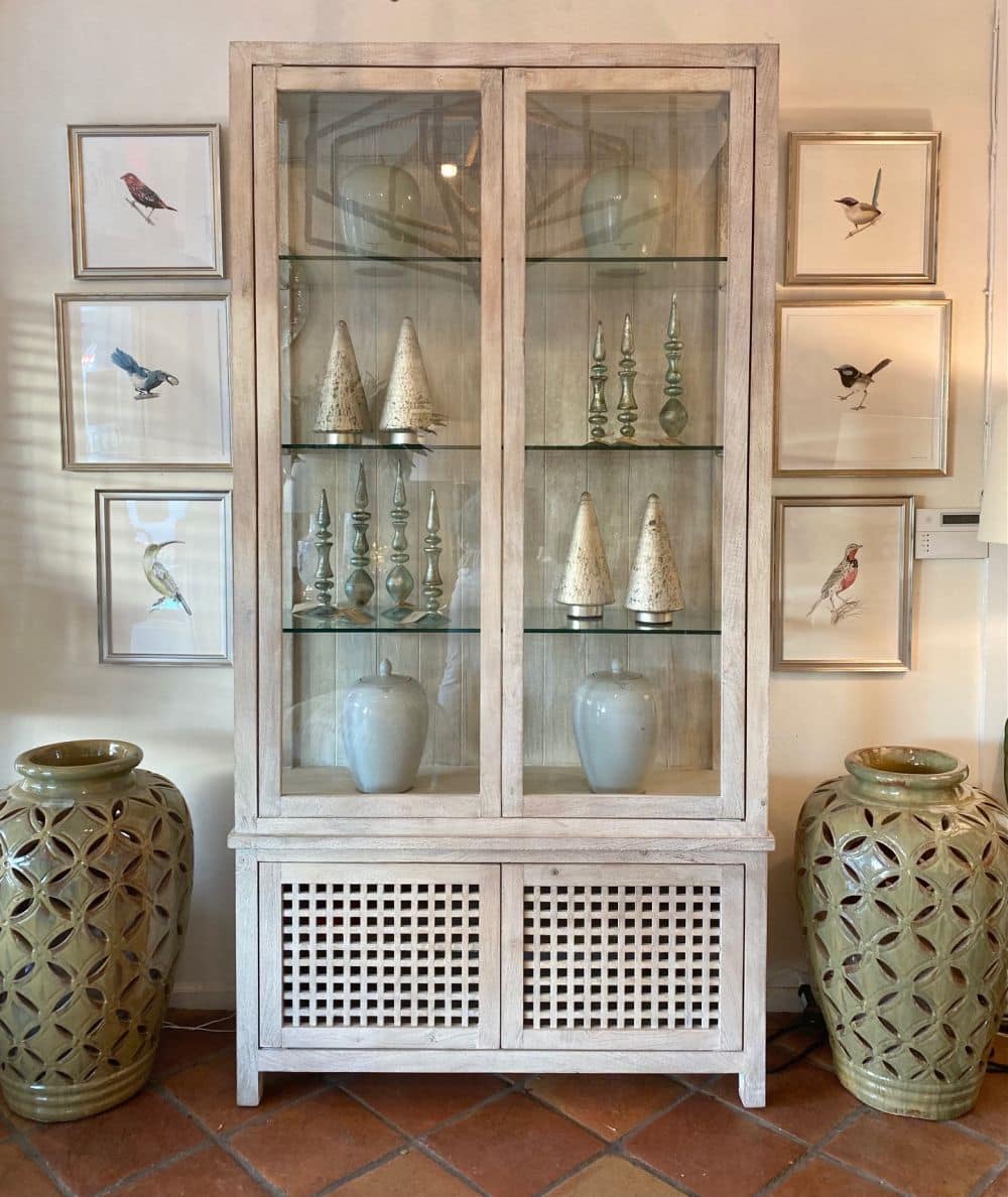 Tall lattice white washed driftwood cabinet with glass shelves and lower closed storage.
