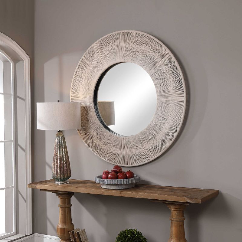Round rope mirror with beige rope and iron frame on a wooden shelf.