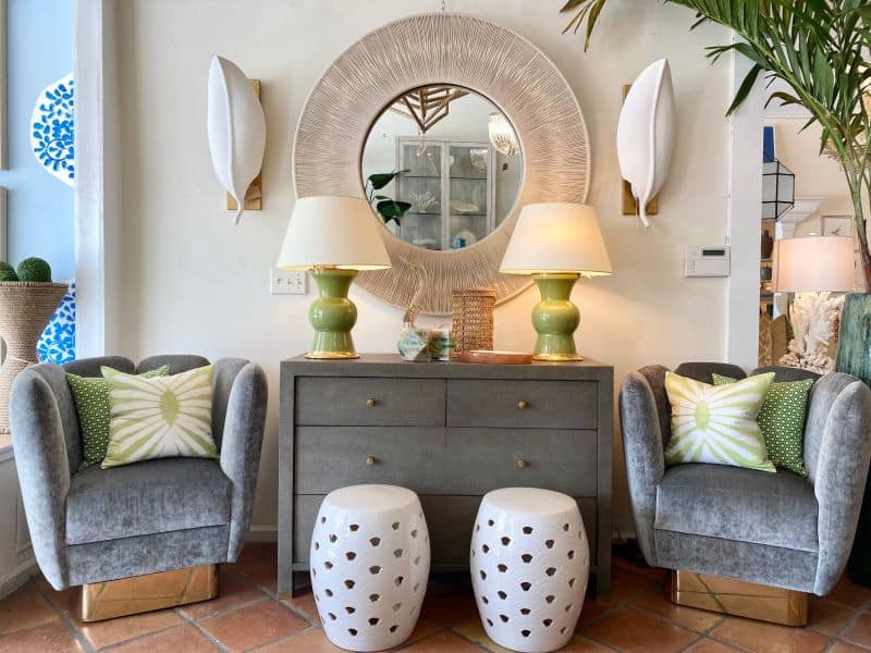 Neutral-colored rope mirror with a solid iron frame situated above a wooden table adorned with decorative objects set against a backdrop of