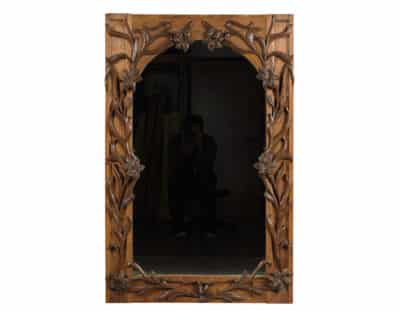 Ornate wooden framed mirror with intricate detailing.