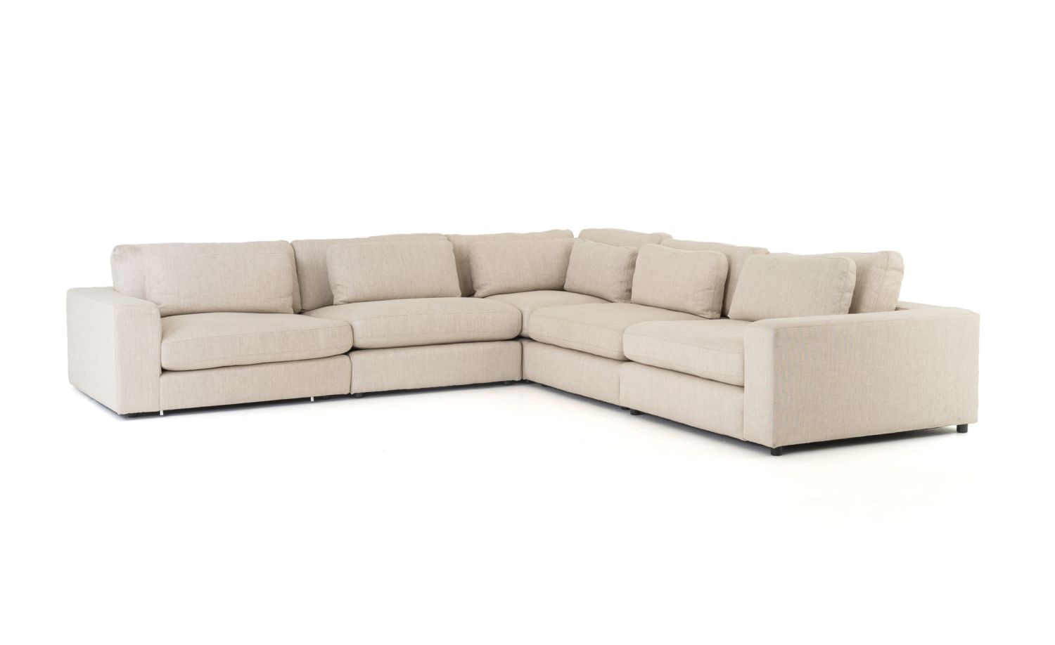 Sectional sofa in natural fabric with multiple cushions and ottoman.