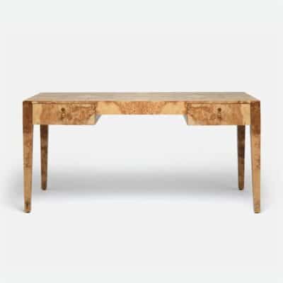 A large rectangular wooden desk made of olive ash burlwood with distinctive faceted brass hardware The desk s rich warm tone contrasts