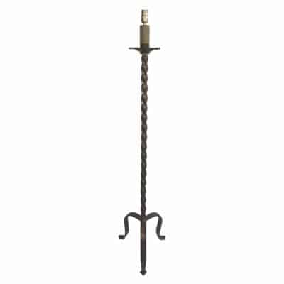 A vintage floor lamp with a twisted gold iron base inspired by candle sticks featuring tripod feet and a gilded finish reminiscent