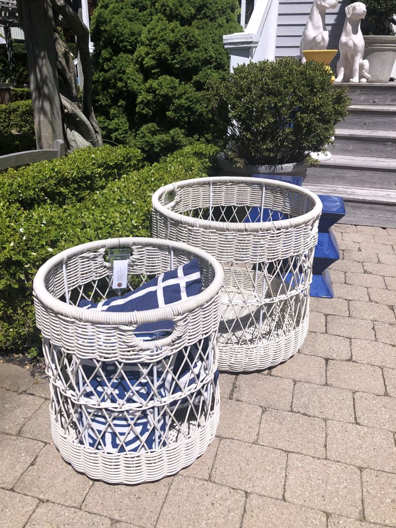 Three outdoor wicker baskets in front of a house, with two larger ones on the left and one smaller on the right.