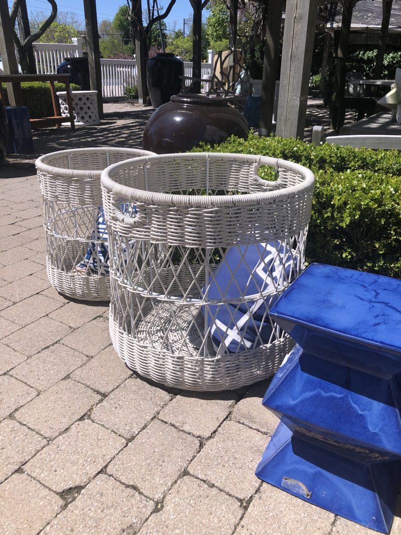 Outdoor faux rattan baskets, two large and one small, on a brick patio with a blue towel.