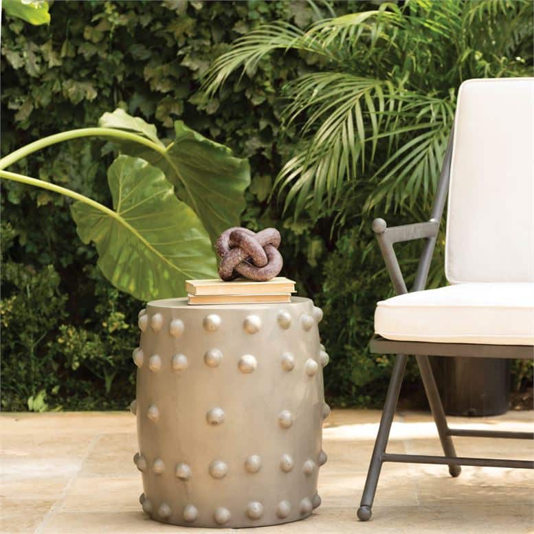 A stone knot-like object on a patio, placed on a table next to a chair.