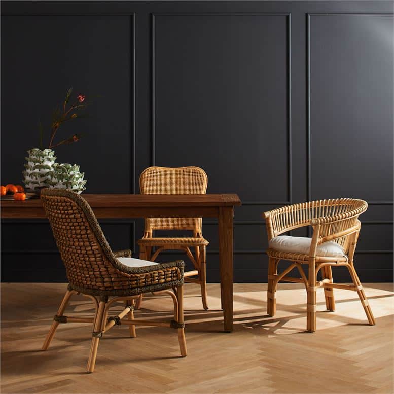 Dark wooden dining table with four chairs, each featuring a barrel back design and woven rattan seat cushions.