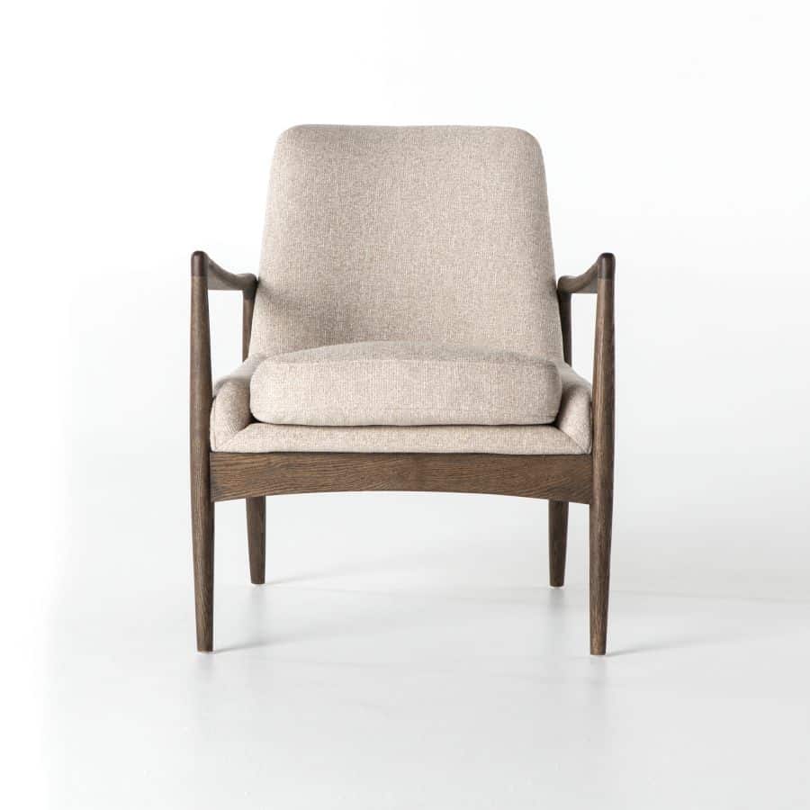 A wooden armchair with light camel upholstery, featuring a curved frame design, set against a neutral background.