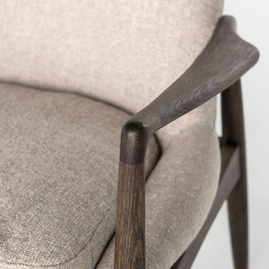 A wooden armchair with light camel upholstery, featuring a curved backrest and warm oak-toned frame.