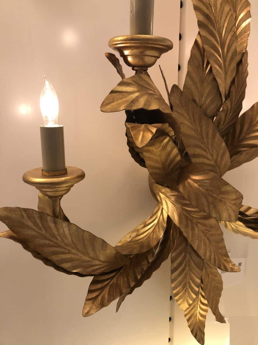 Antique gold wall sconce with laurel leaves and candles.