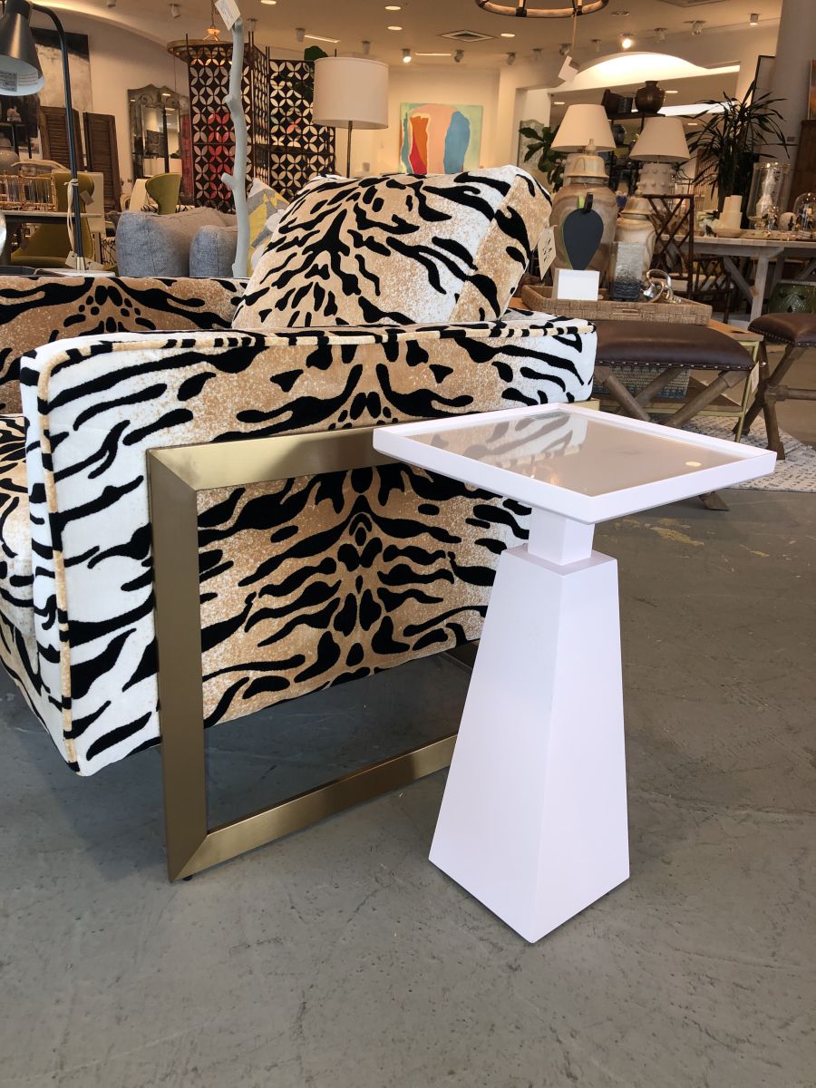 A zebra print armchair with a gold frame and a small square side table next to it in a store.
