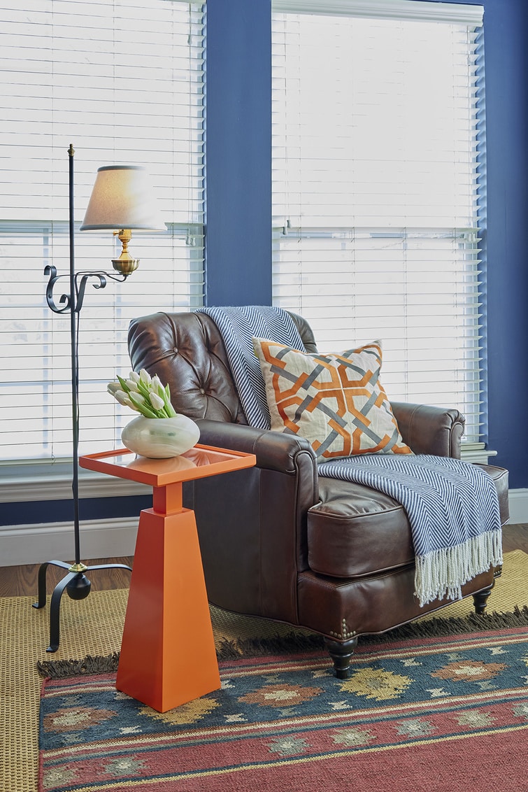 A red and white checkered pillow on a brown leather armchair.