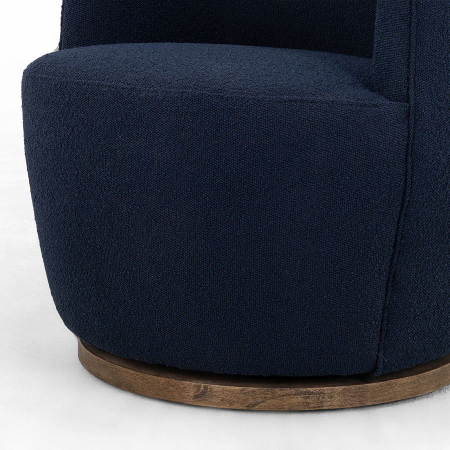 Blue upholstered petite swivel chair with a natural parawood base, positioned sideways against a white background.