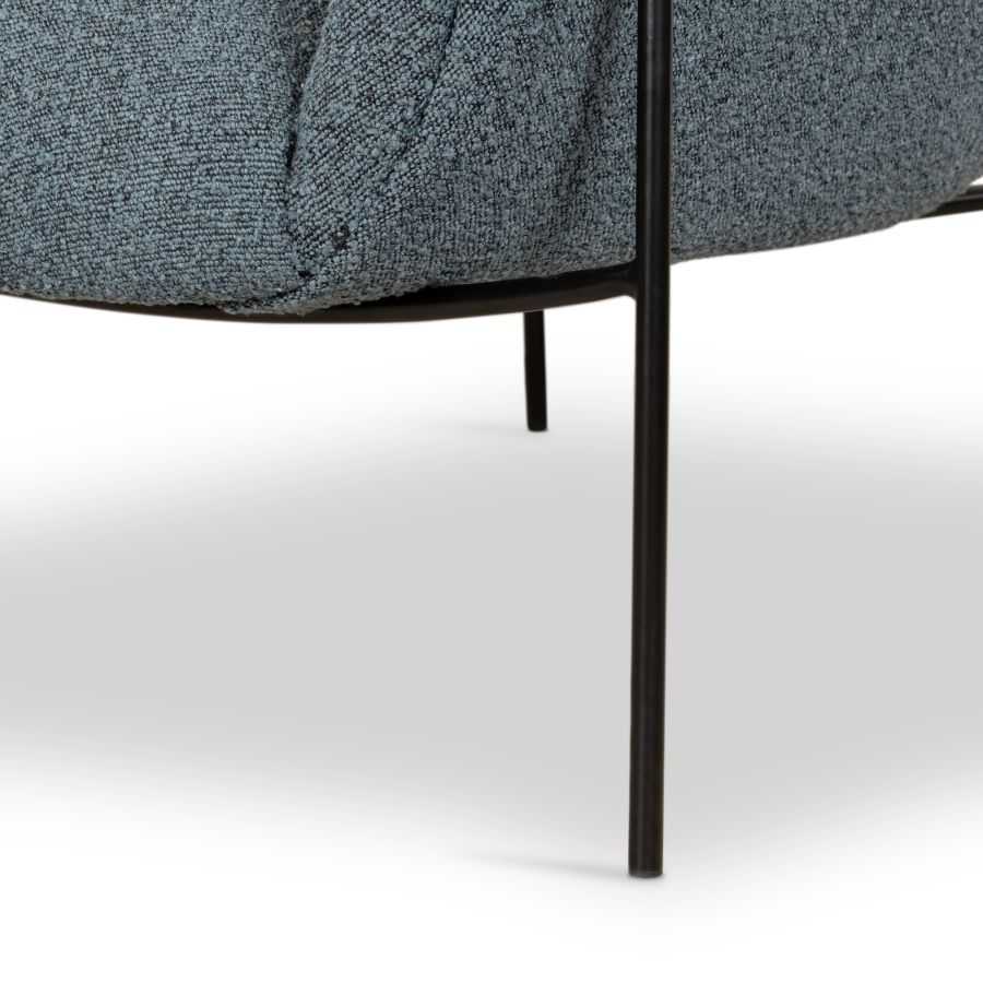 Mid-century style boucle chair presented in a clear image focusing on its design showcasing the material texture and the slender black iron