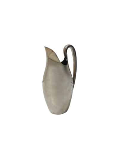 This is an image of a vintage S. P. pitcher with a metallic finish, placed on a surface against a white background.