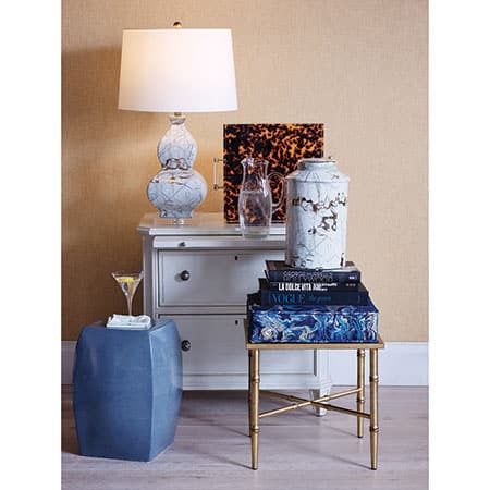 A stylish acrylic tray with tortoise coloring and brushed brass accents, placed on a table next to some decorative items.