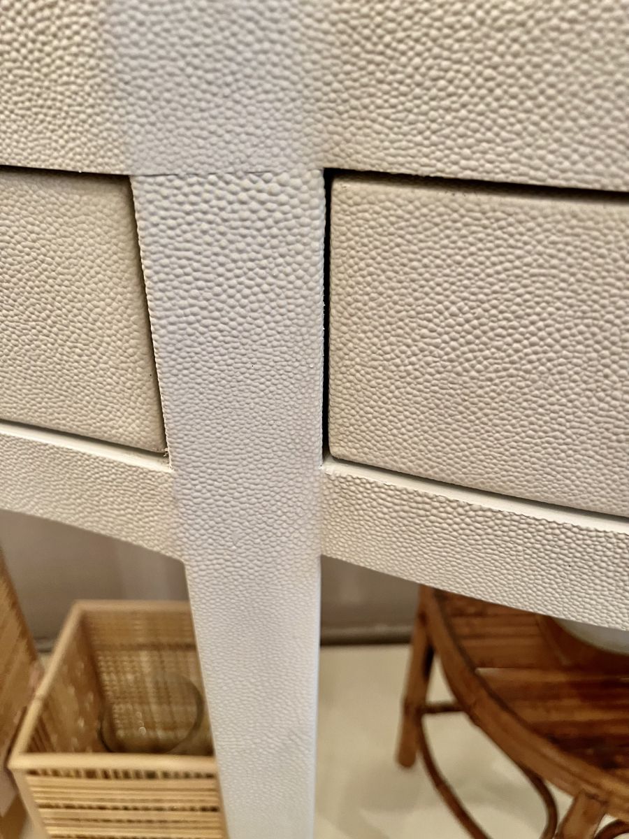 Ivory faux shagreen serpentine front console with brass finished keyhole hardware, tapered legs with satin brass ferrules.