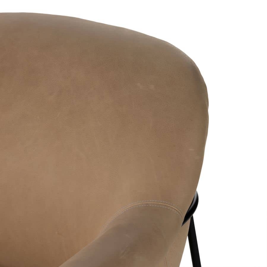Close-up of a plush butterscotch leather chair with black iron legs, showcasing its mid-century design.