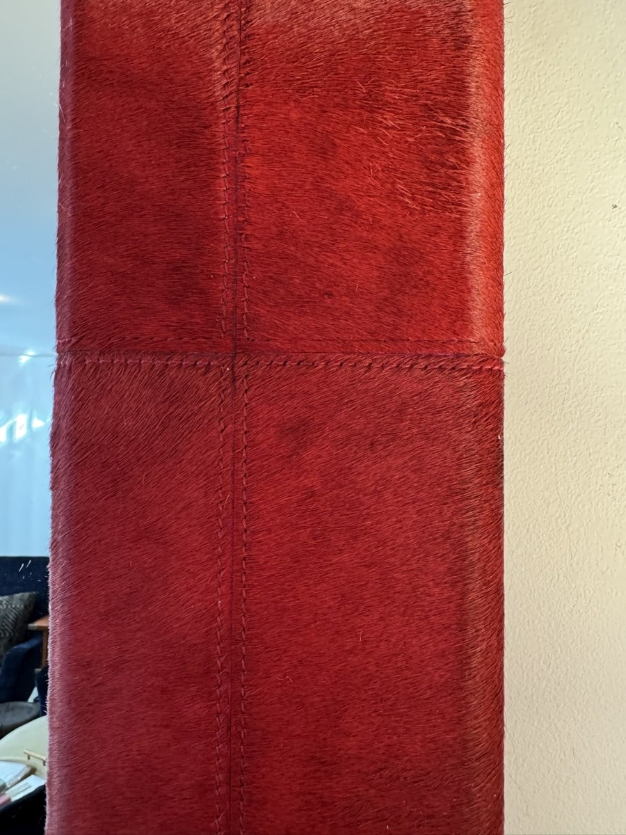 Close-up of Tauro Wall Mirror featuring vibrant red hair-on-hide patterned pieces arranged in a modern quilted design, highlighted by double stitch detail.