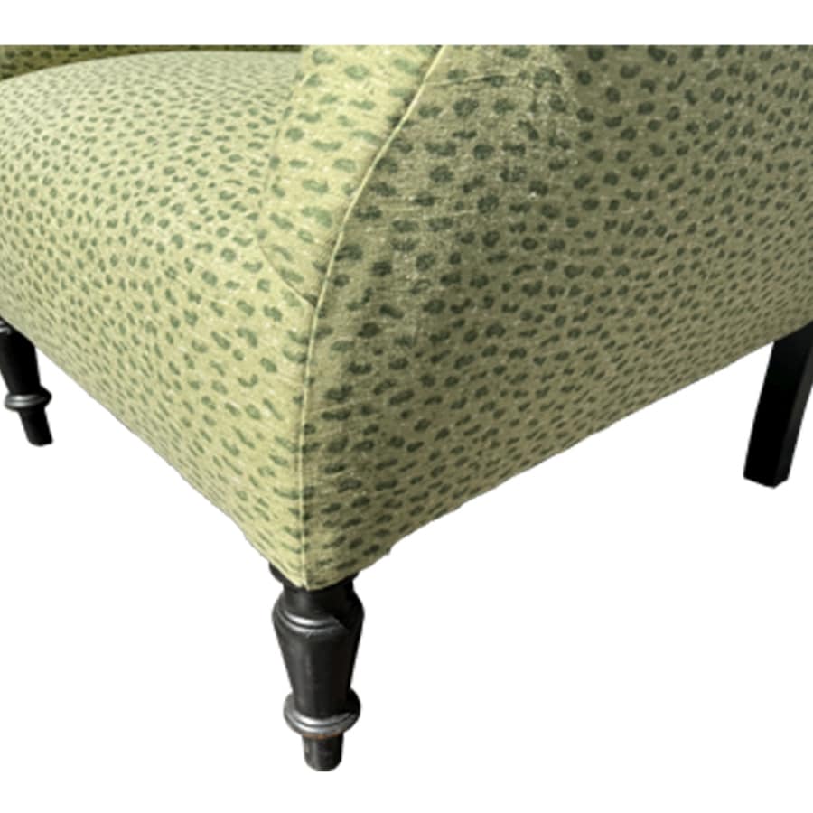 Close-up of antique upholstered chair with rolled arms and nailhead detail, showcasing intricate fabric pattern and plush comfort.