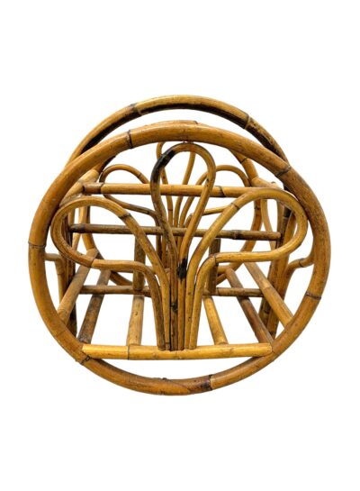 Close-up of vintage mid-century rattan magazine rack with round frame and three leaf decorative shapes on sides.