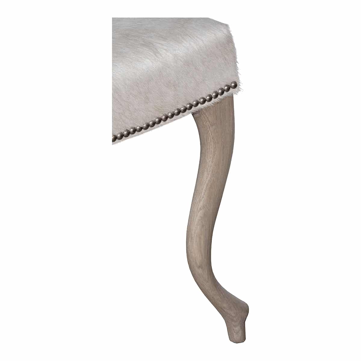 Close-up of hide ottoman with curved wood legs, featuring platinum nailhead trim on Serengeti natural grade 7 hide.