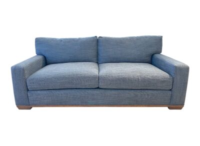 Blue upholstered apartment sofa with weathered grey legs, showcasing elegant design for comfortable living room seating.