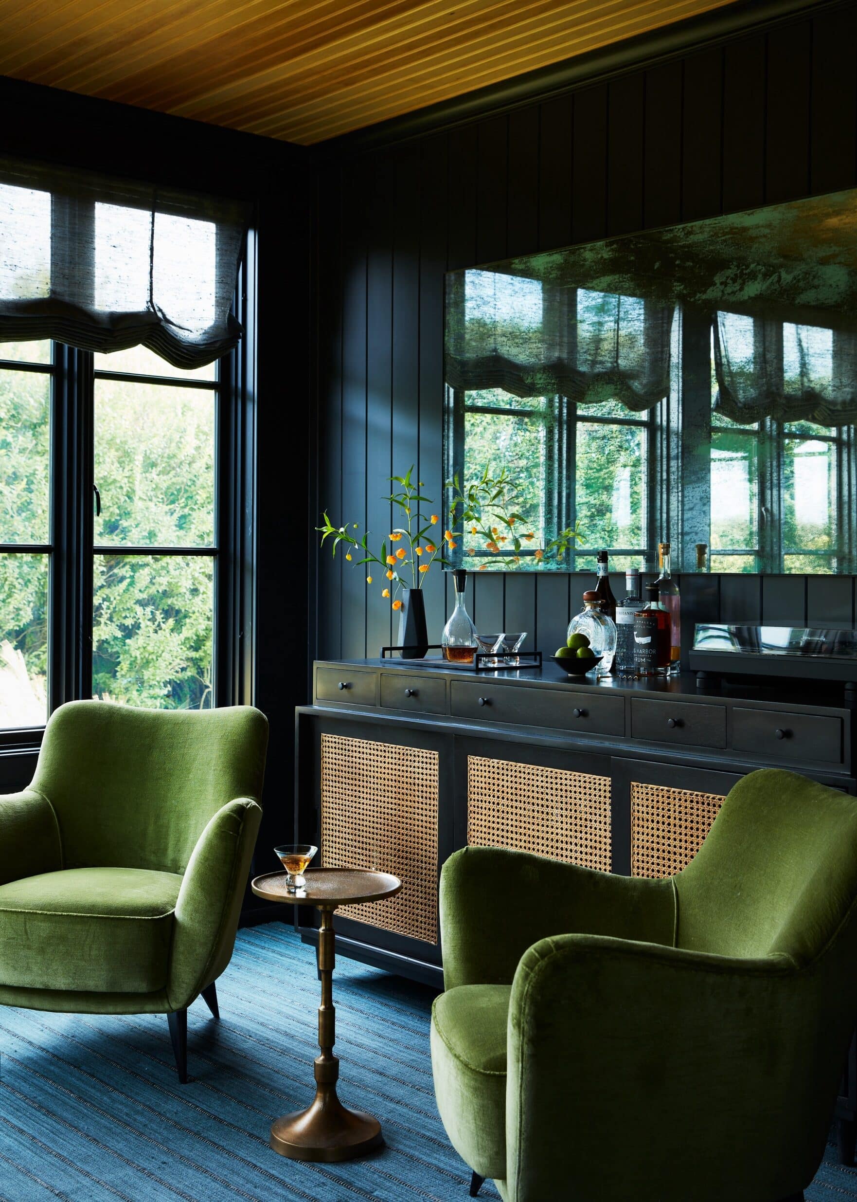 Chic living room setting featuring vintage-style armchair, wooden bar area with mirror, and colorful decor accents.