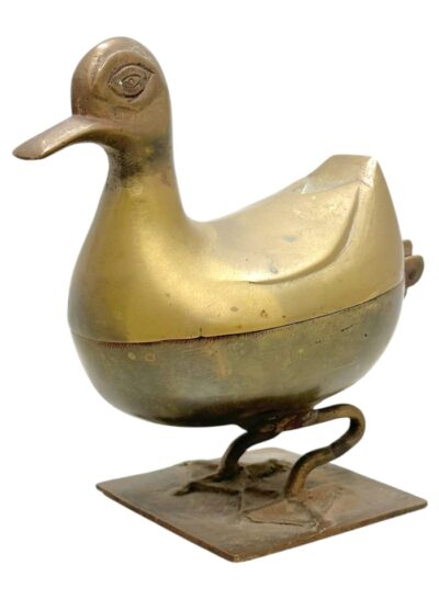 Close-up of vintage brass bird box with unique design features, including eye detail on side.