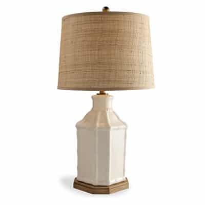 A ceramic lamp with bamboo motif on wooden base and raffia shade.