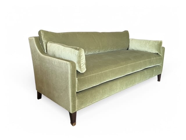 The Meadow Velvet Apartment Sofa, upholstered in luxurious V-grade velvet, featuring pecan wood legs and brass ferrules, with two plush throw pillows.