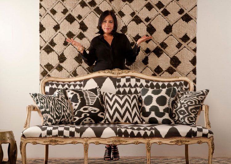 Woman sitting on colorful patterned couch, posing with hand on hip.