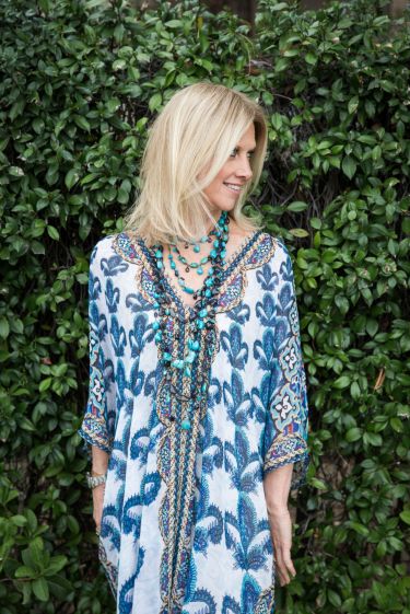 Close-up of woman wearing a blue and white floral dress with vibrant turquoise necklace.