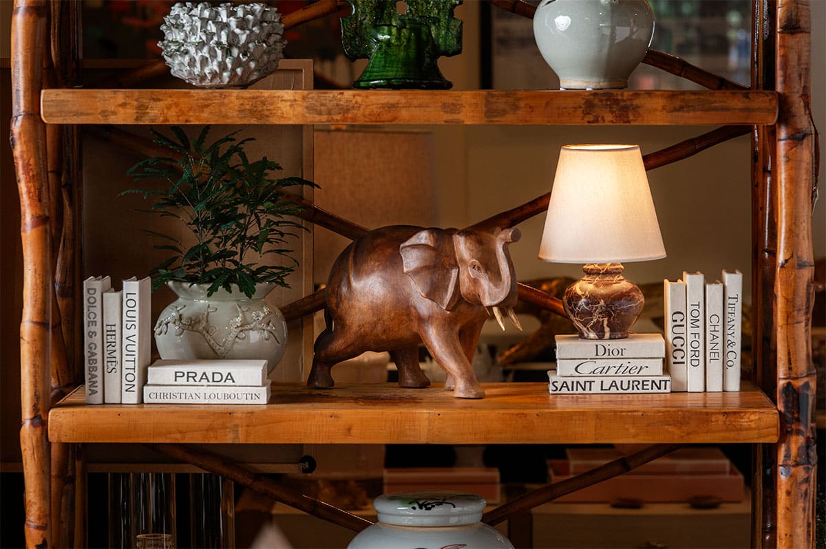 Vintage carved wood elephant on shelf, aged patina, two tusks raised trunk, small chip ear.