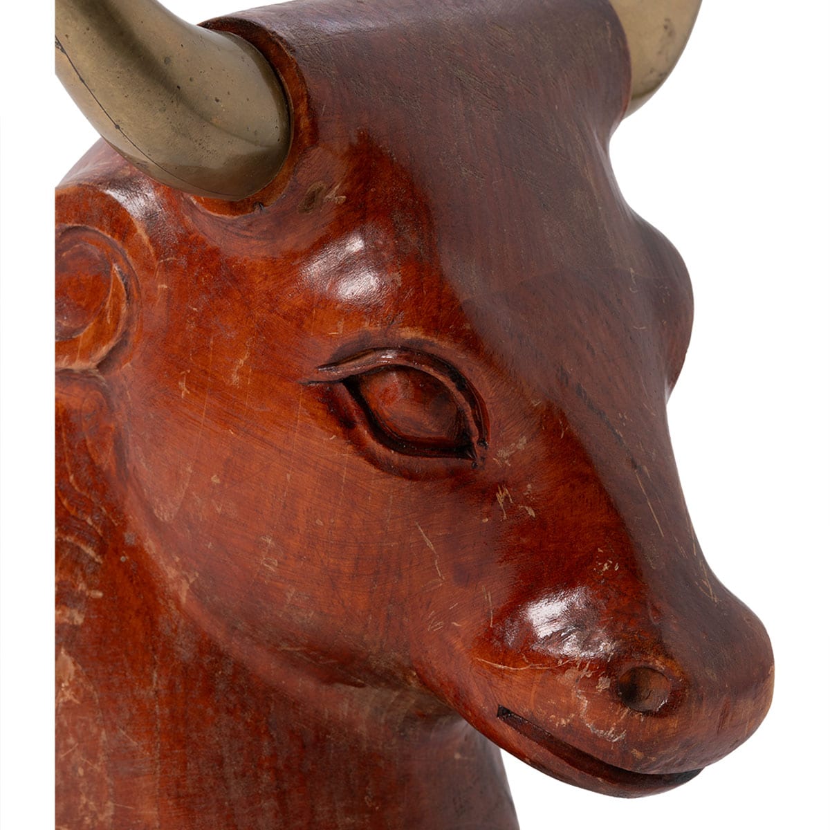Close-up of vintage wooden bull head sculpture with brass horns, showcasing intricate carving details.