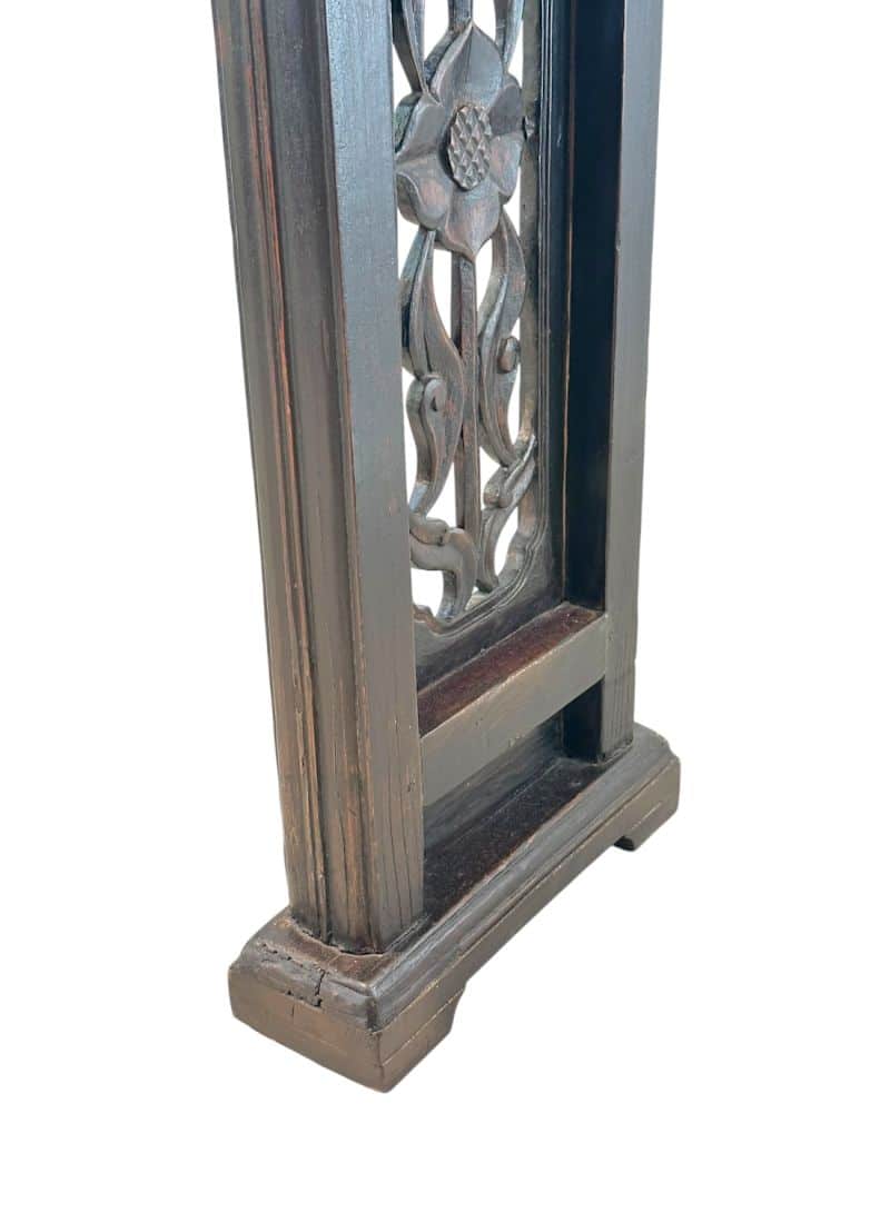 Close-up of antique Chinese console table, featuring intricate carved fretwork on legs and apron, with an aged lacquered finish.