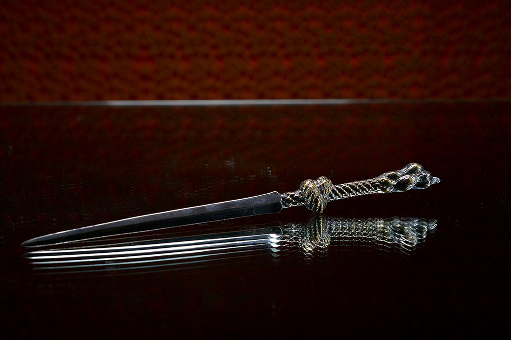Vintage silver plated rope letter opener on a reflective surface