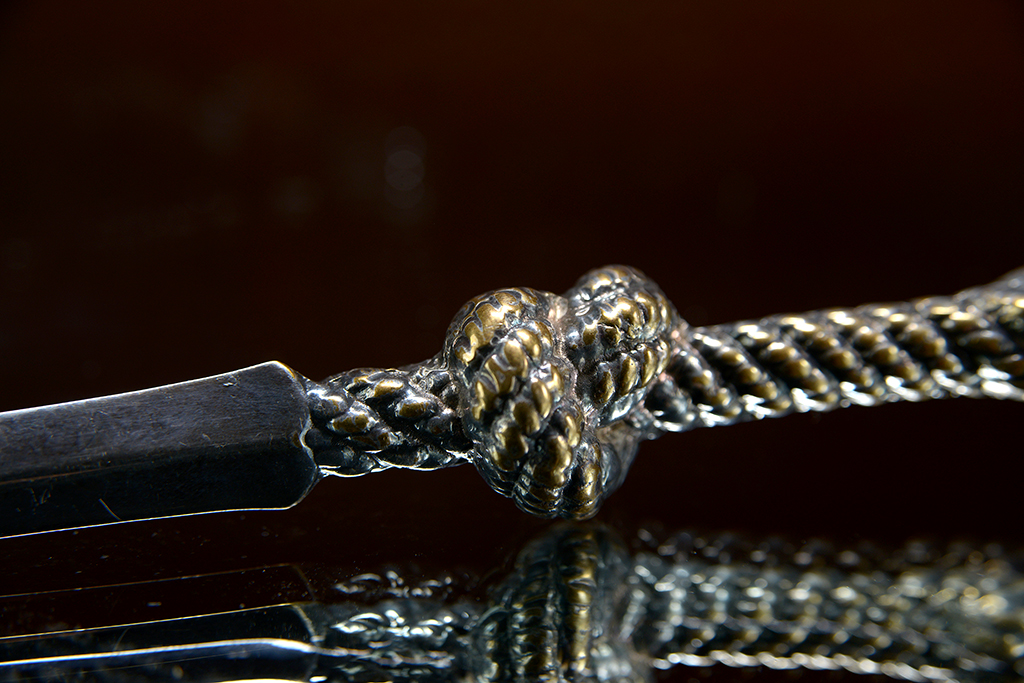 A vintage silver plated rope letter opener with a twisted metal handle, showcasing its intricate design and craftsmanship.