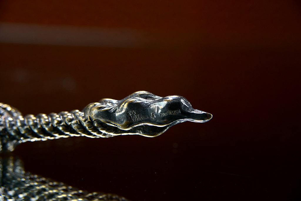 A close-up image of a vintage silver plated rope letter opener with intricate detailing, set against a dark background.