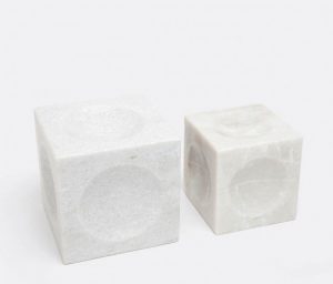 Two square marble cubes with spherical depressions on a white background.