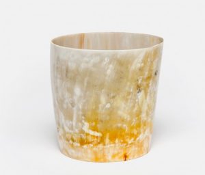 The image displays a large cylindrical vase with a natural horn texture on its surface It is predominantly brown and yellow in