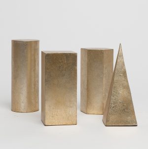 Four golden metallic objects, including a cylinder, hexagonal prism, square pyramid, and rectangular cuboid, displayed on a white surface.