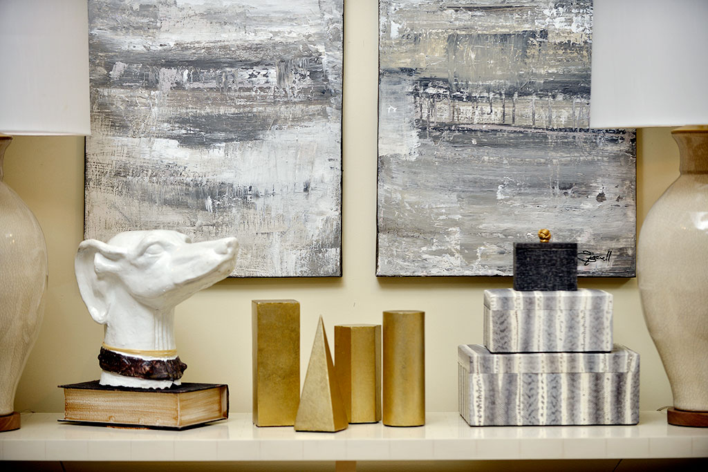 A collection of brass decorative objects on a shelf, including cylinders, hexagonal prisms, square pyramids, and rectangular cuboids.
