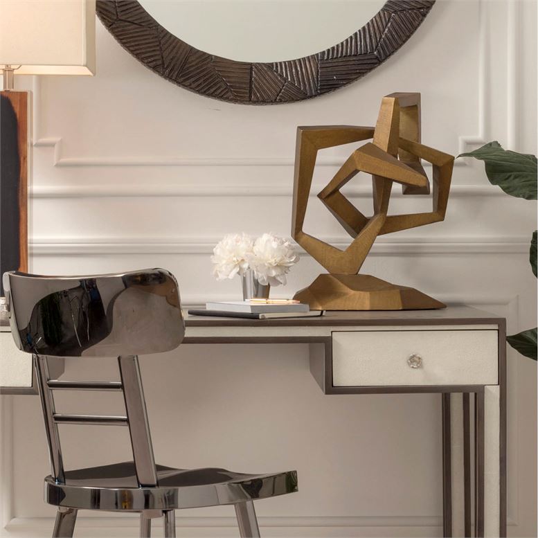 A modern desk with a sleek design featuring a sculptural art piece on top and a chair in front The desk is