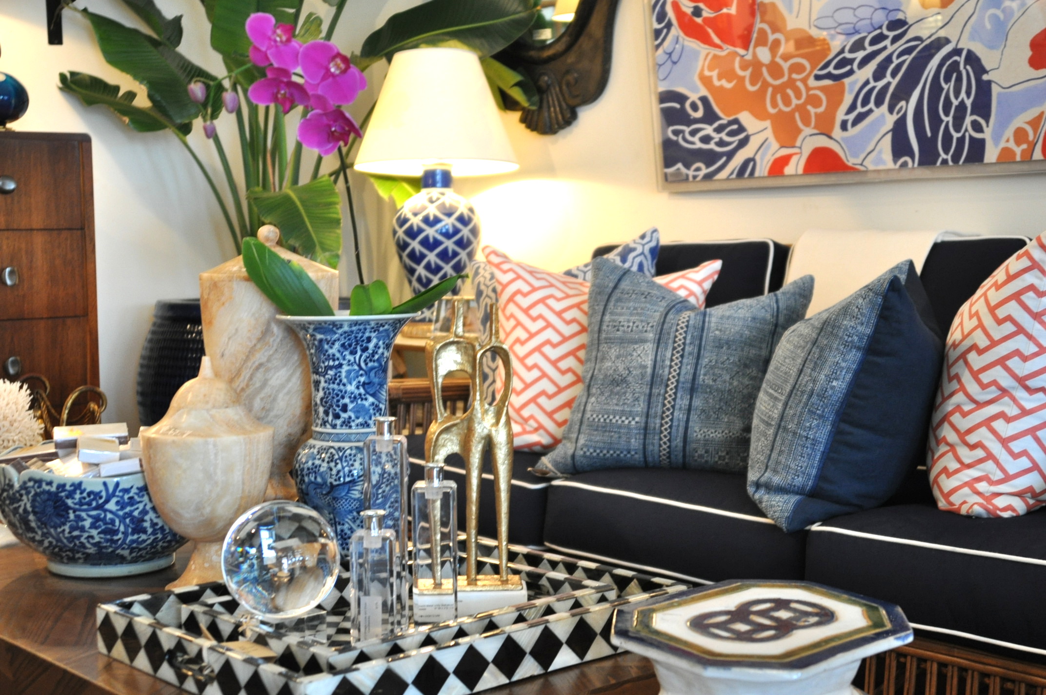 A room with a couch pillows and various decorative items such as vases and sculptures The couch has a blue and white