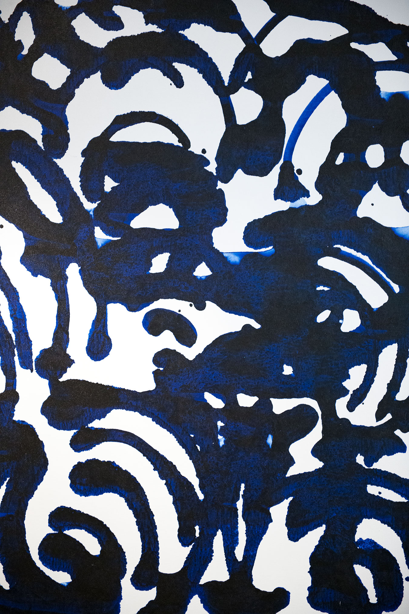 The image is a photograph of an abstract art piece with a blue and black color scheme featuring swirling patterns and shapes