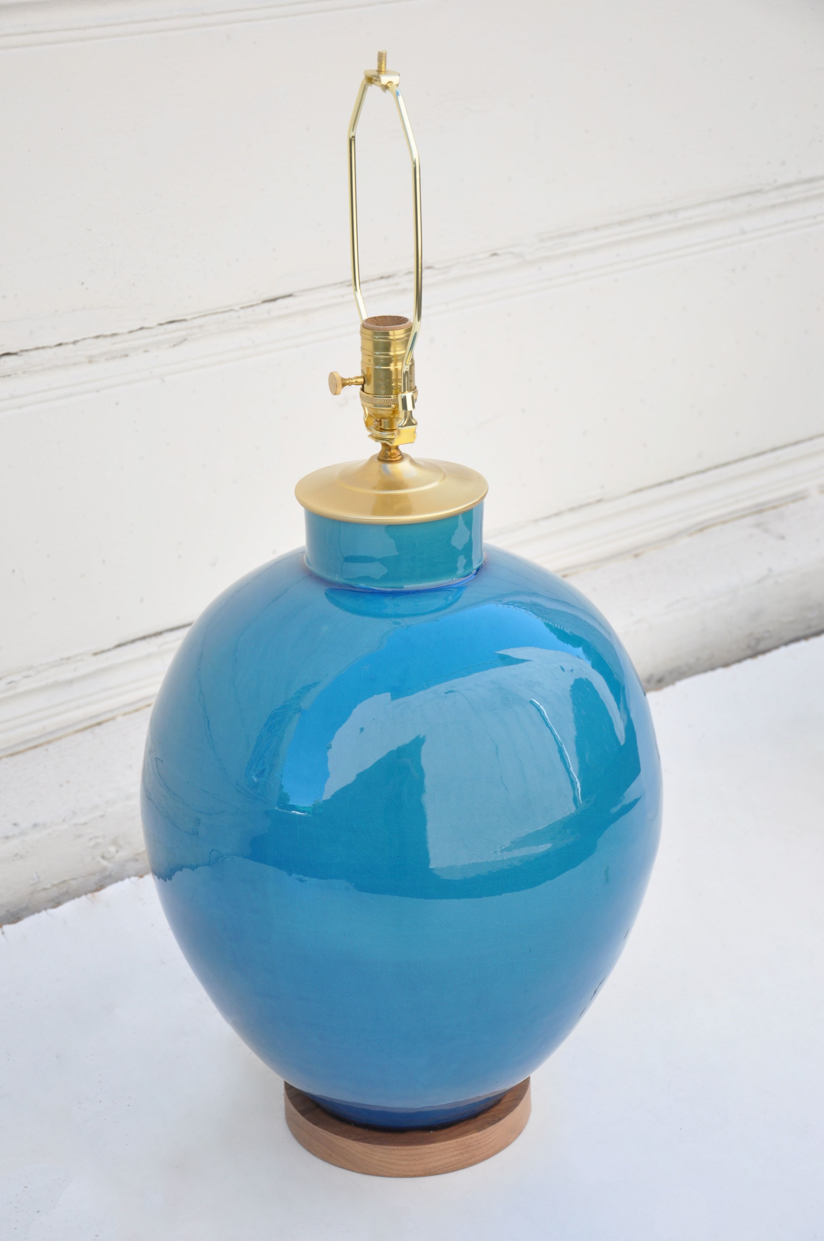 A blue ceramic lamp with a crackled finish, sitting on a wooden surface.