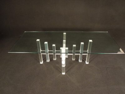 Vintage rectangular lucite coffee table with a glass top and metal rod connecting lucite blocks in cross form.