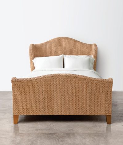 Woven seagrass bed with a headboard and two pillows, presented in a studio setting against a white background.