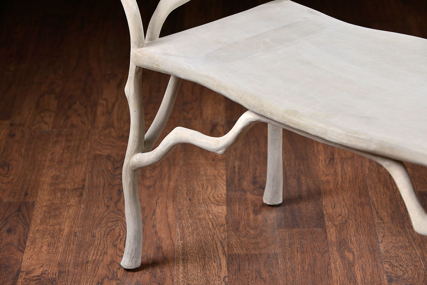 Faux bois concrete bench with twig details, set against a wooden floor.